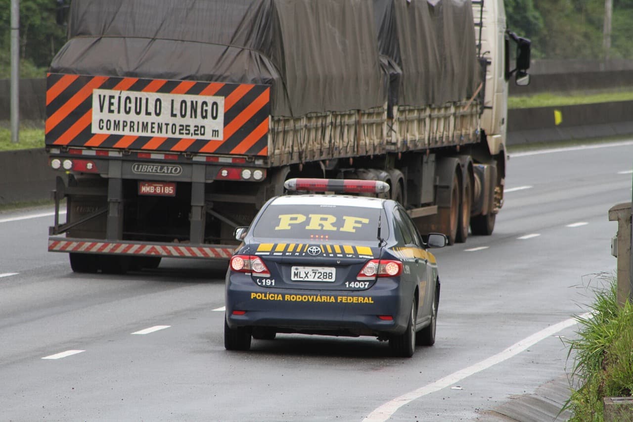 Rodovia federal com sinalização e movimentação de caminhões pesados